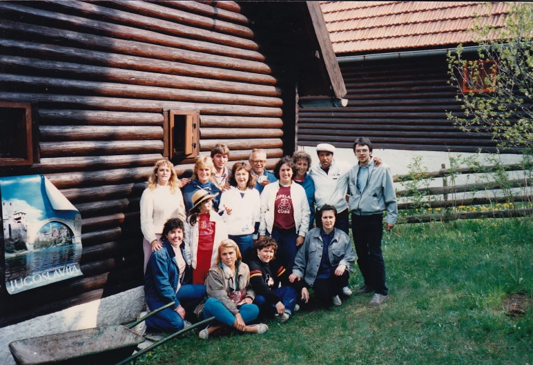 many people stand near the side of the log cabin