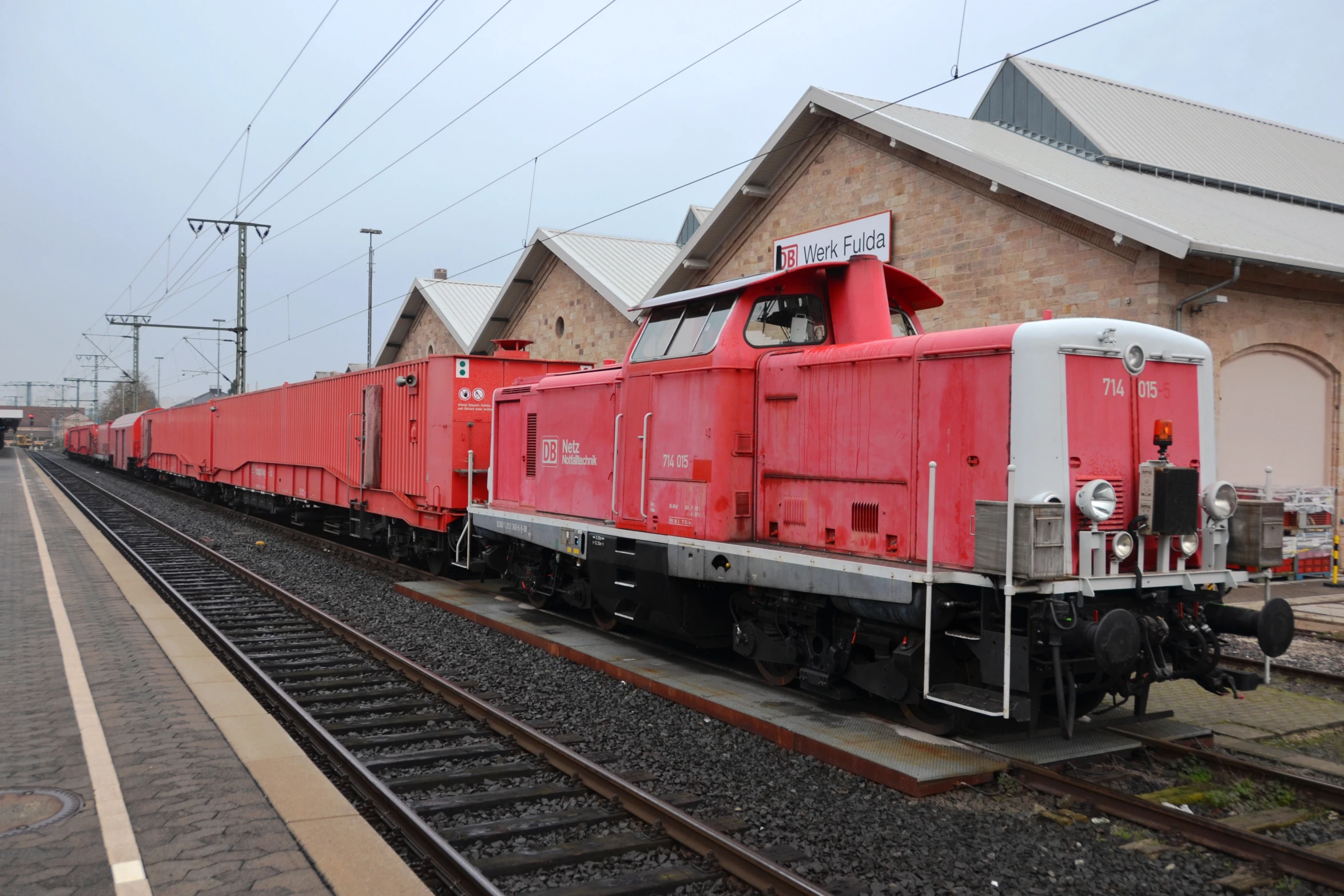 a red train is pulling into a station