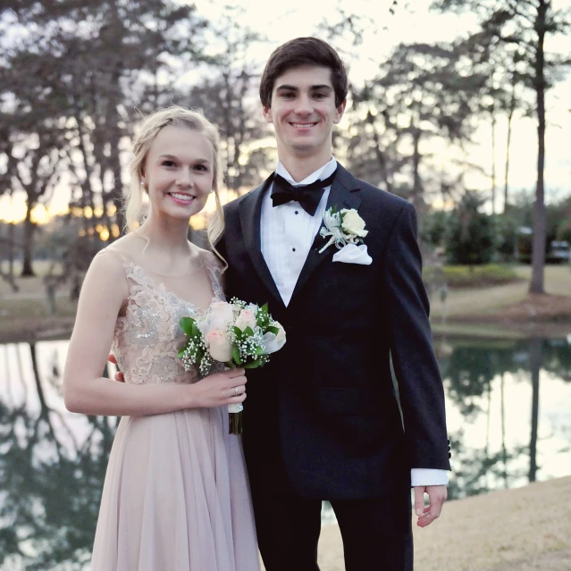 a man and woman posing together by a pond