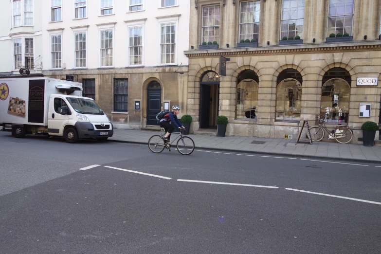 a person riding on a bike on the street in front of a food truck