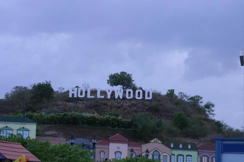 a hollywood sign sits atop a hill on a cloudy day