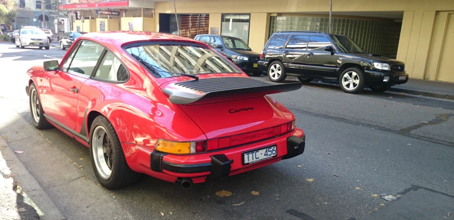 a red car parked next to two black cars