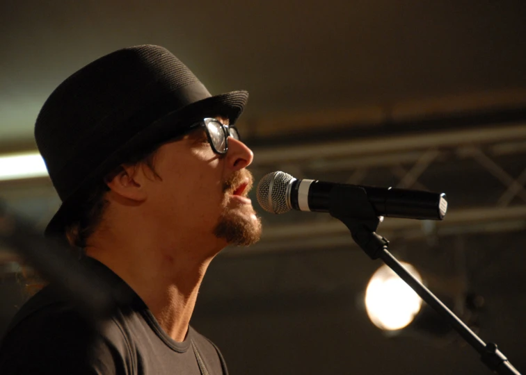 a man singing into a microphone while wearing glasses
