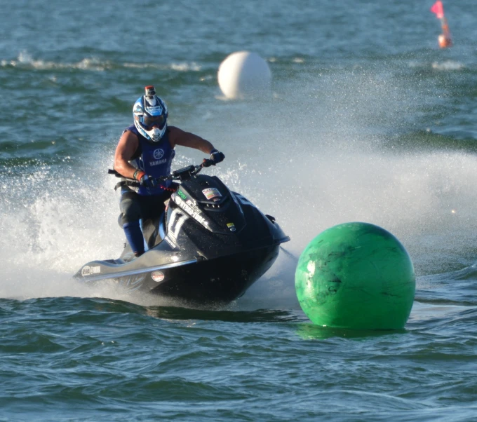 a man on a jet ski riding next to a buoy