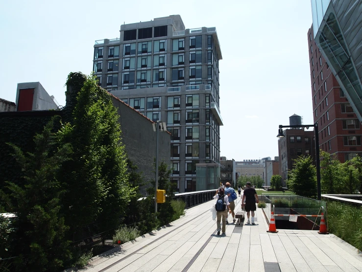 people walking over the top of a bridge between two tall buildings