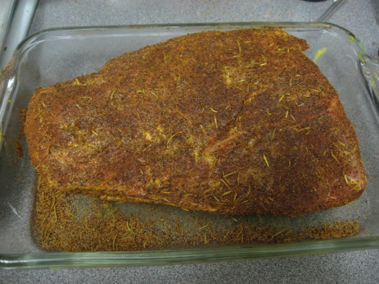 a square glass dish holding seasoned beef steak