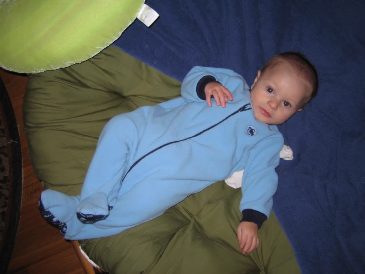 a little baby that is laying down with a blue hoodie