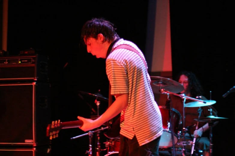 a man playing the drums on stage next to other instruments