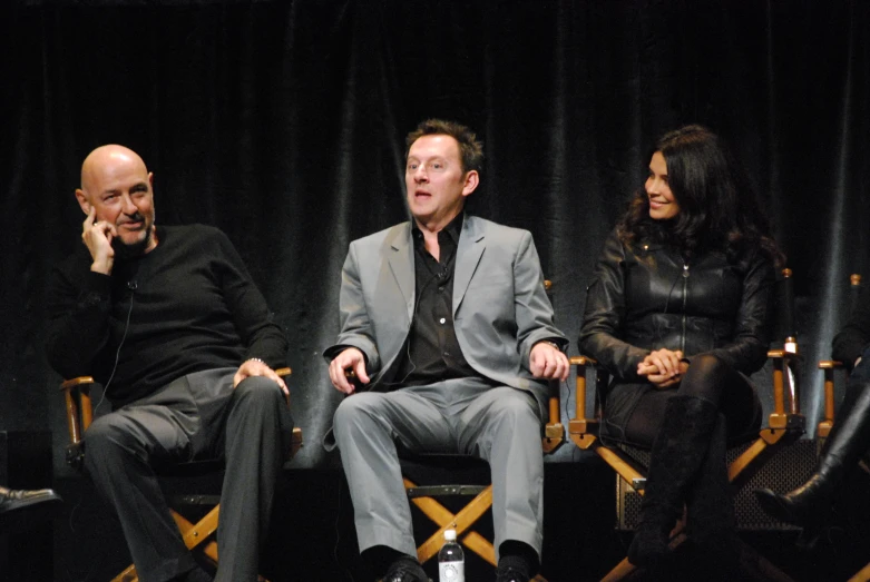 three people sitting in chairs on stage talking