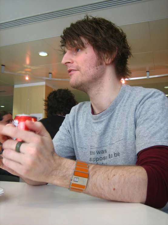 a man sitting at a table holding a cell phone