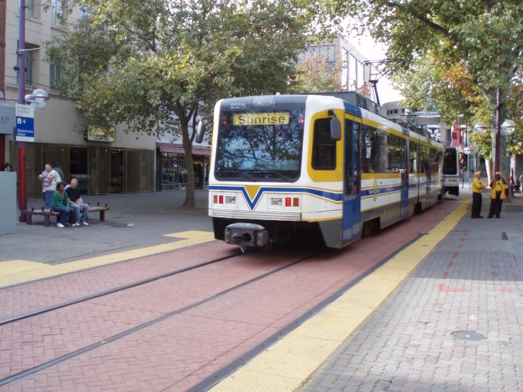 a yellow and blue tram parked on train tracks next to buildings