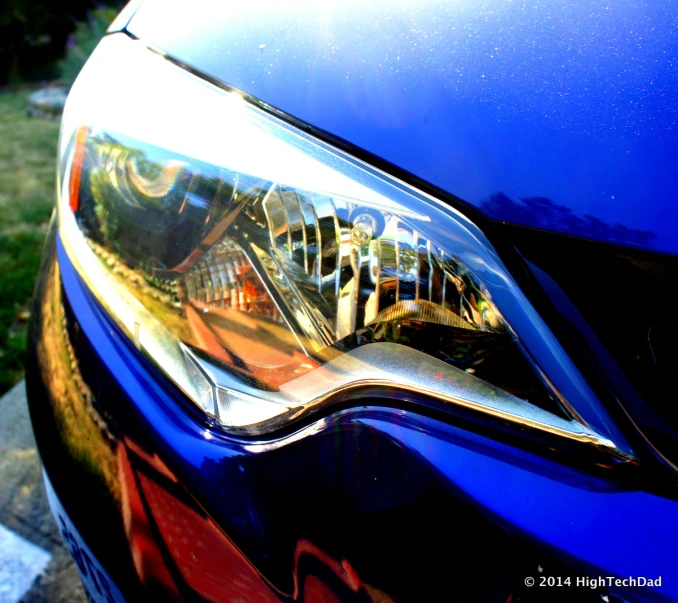 the front lights on a blue car in the sunlight