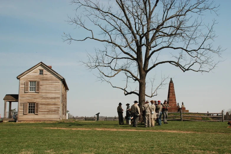 group of people standing near tree in field on sunny day