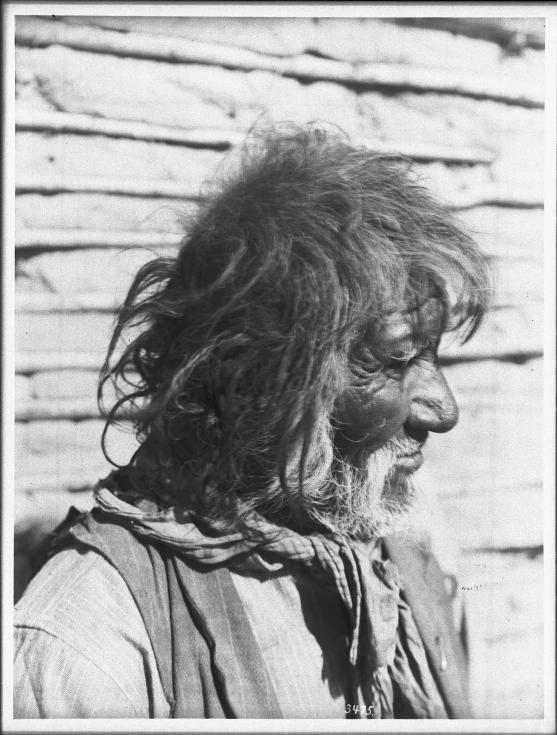 an old man with long hair and beard standing in front of a brick wall