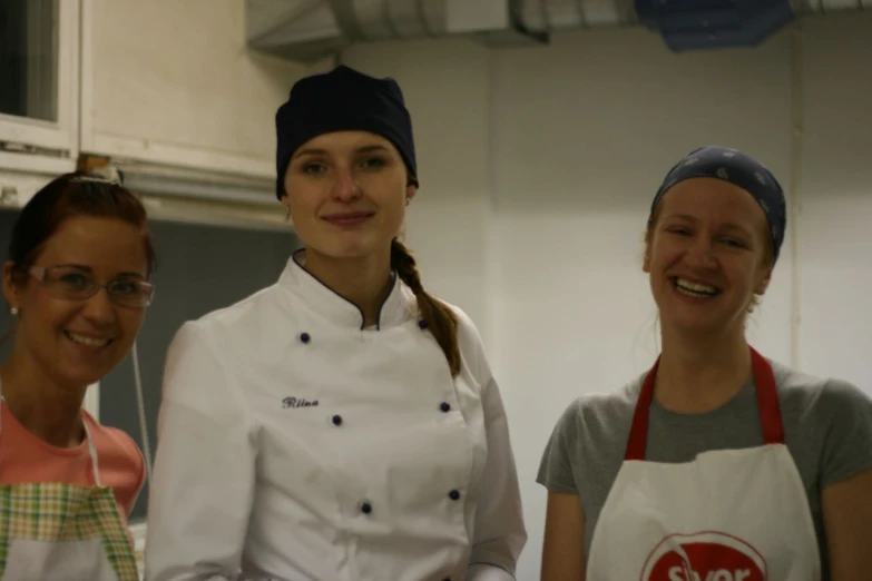 three chefs smile at the camera as they stand behind them