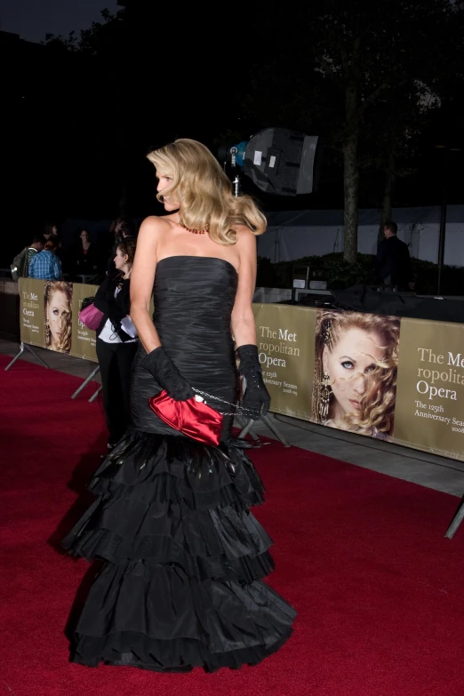 a woman wearing a long black dress standing on a red carpet