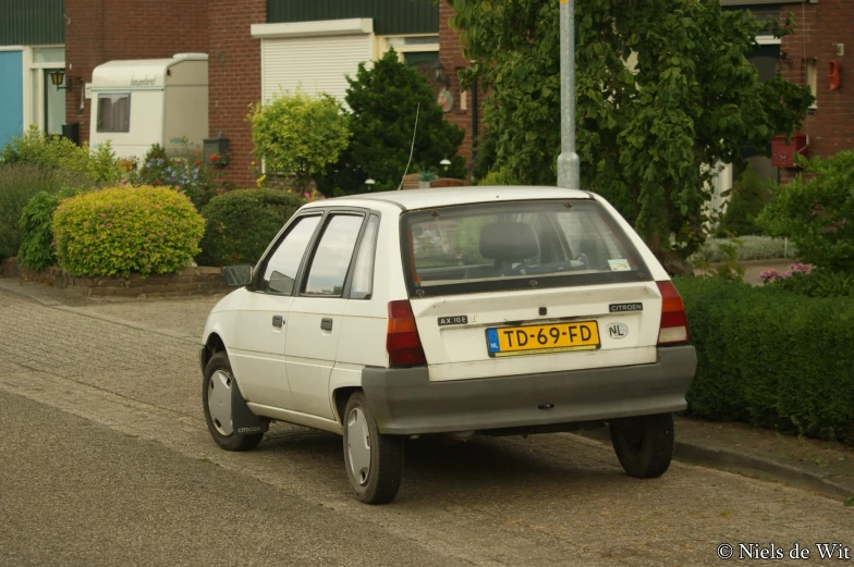 a white car parked in front of two brown buildings