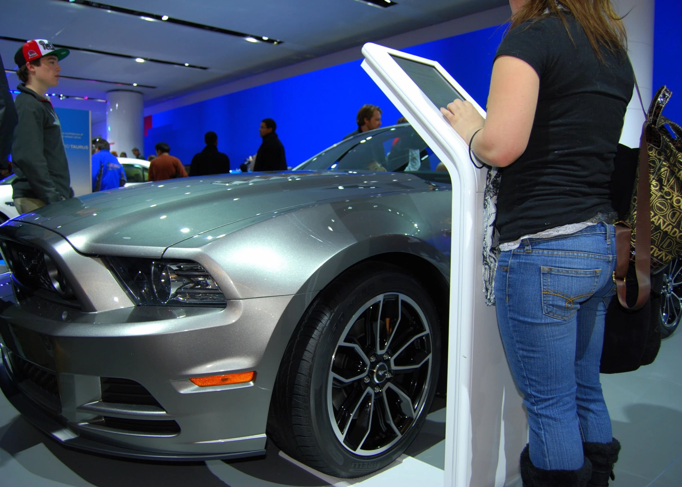 a young woman checks out a silver mustang