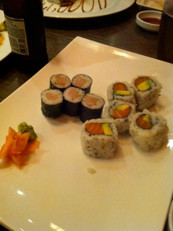 a plate with sushi, carrots and wine on the table