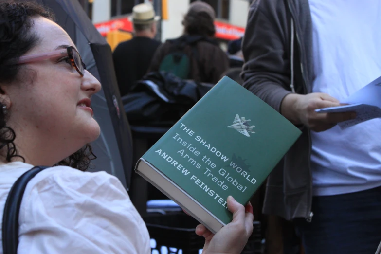 an emptient green book in the hand of a woman in glasses