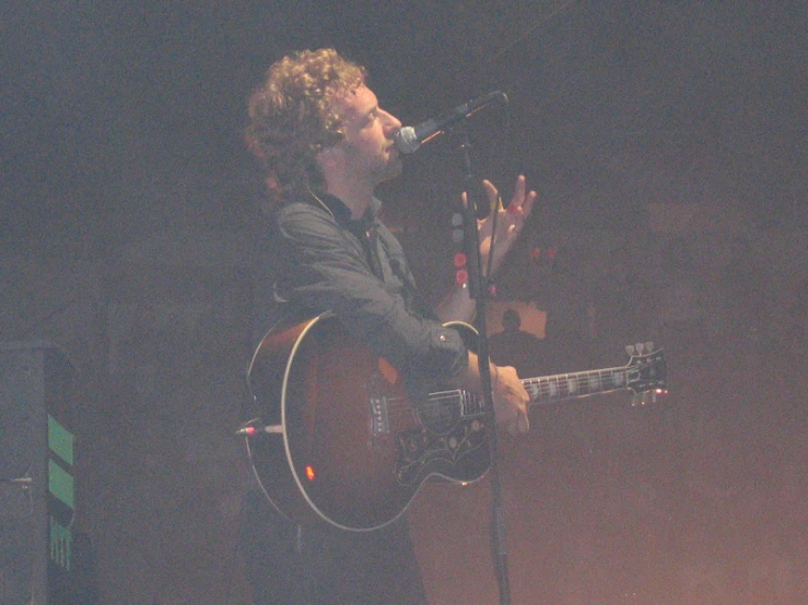 a man that is holding a guitar up to his ear