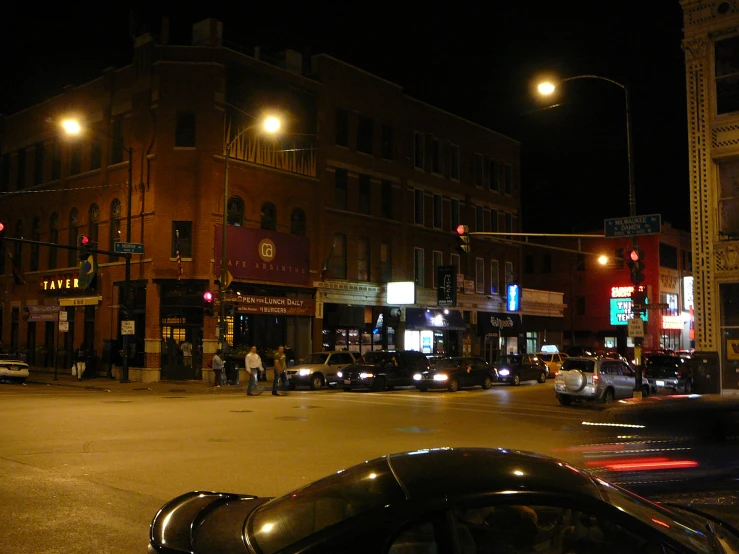 an intersection with cars parked on it, with streetlights at night