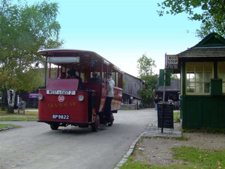 a trolley traveling past a train station next to a green building