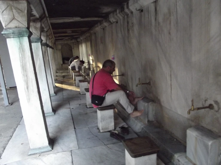 a man in red shirt sitting on top of two stools