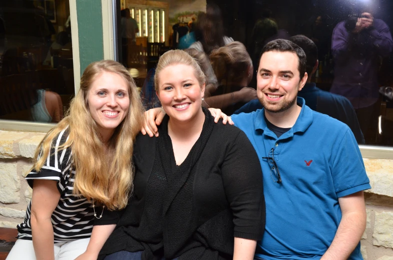 two young ladies are sitting next to a man