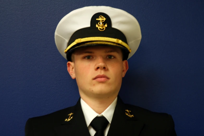 a navy officer in front of a blue wall