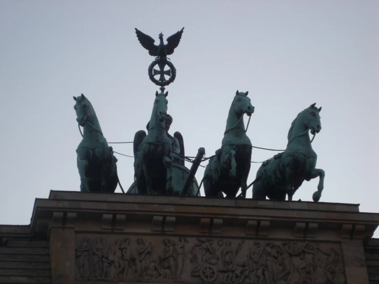 statue on top of large building with four horses in front
