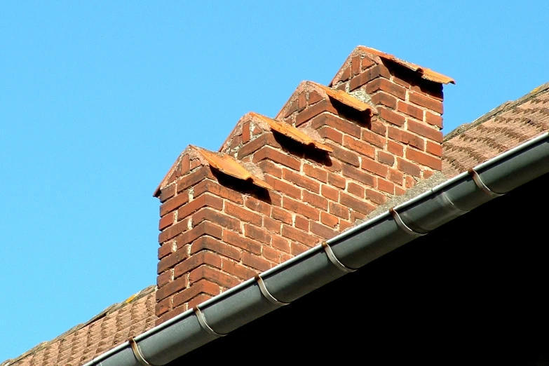 a brick wall with a roof ventilator against a blue sky