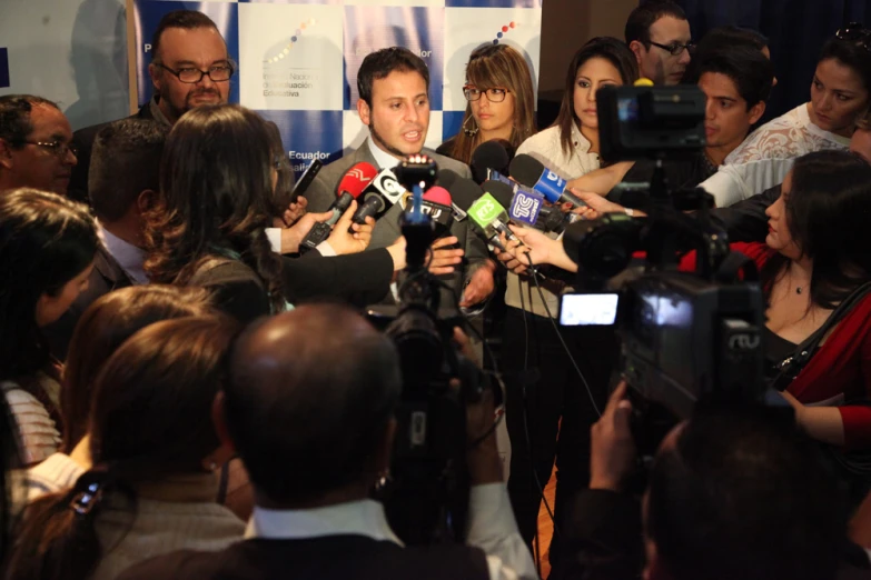 a man surrounded by press and reporters
