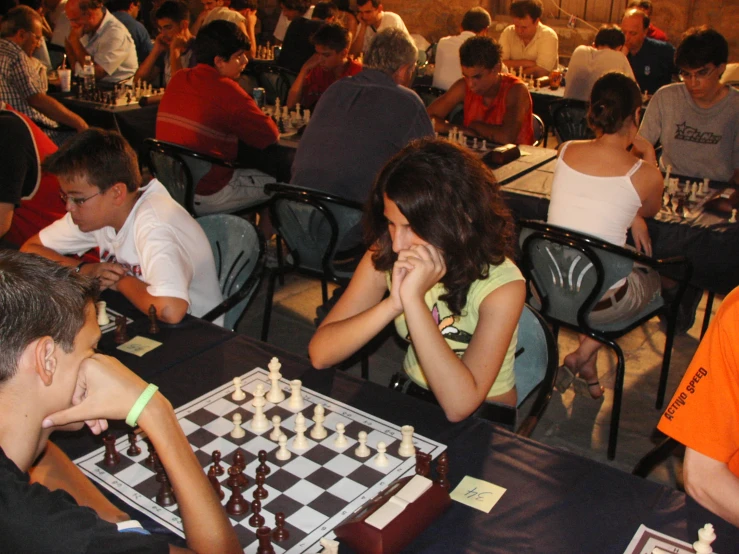 a game of chess with several people sitting down