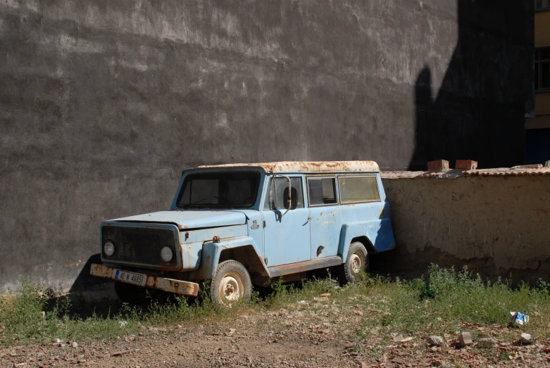 an old dirty off road vehicle parked next to a cement building