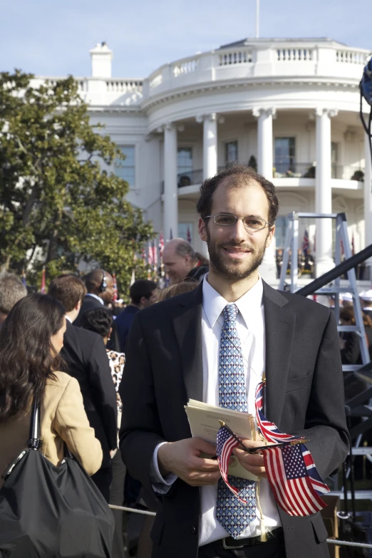 a man wearing a suit is standing in front of a white house