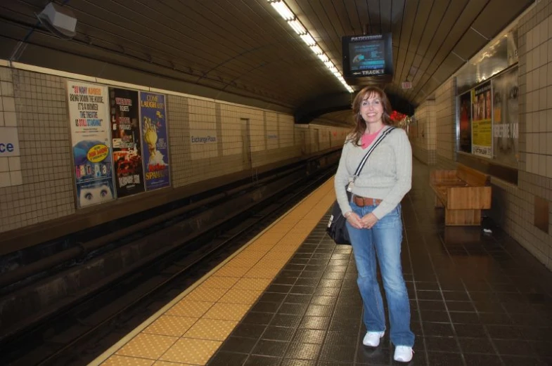 a woman standing in the subway next to a train