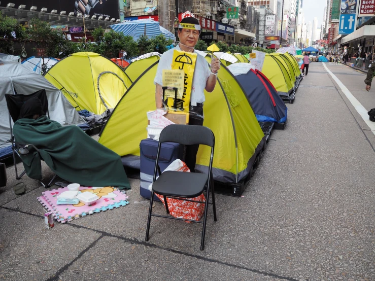 a man in a cap sits in front of some tents on the side of the street