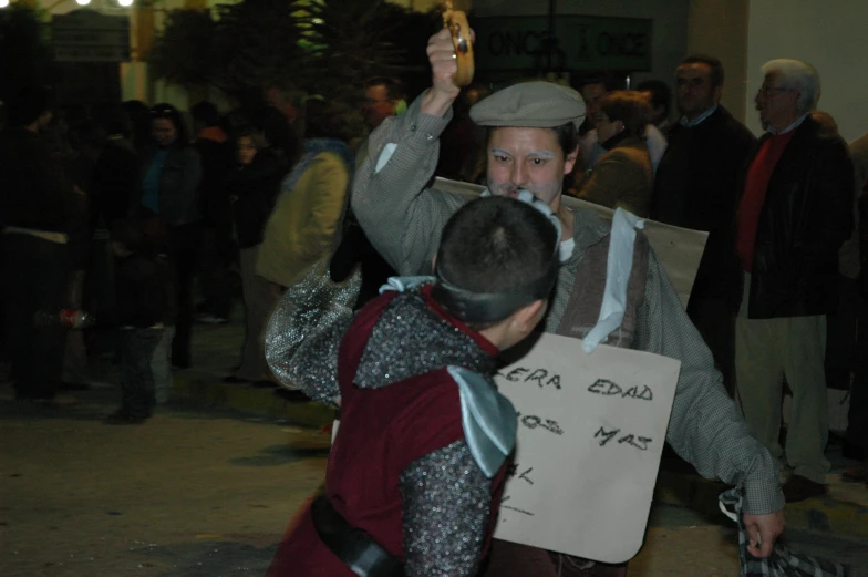 people gather on the sidewalk as one holds a cardboard sign that reads get equal too may