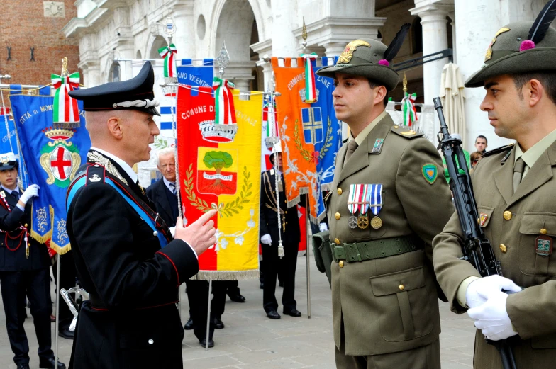 a couple of men in uniform standing next to flags