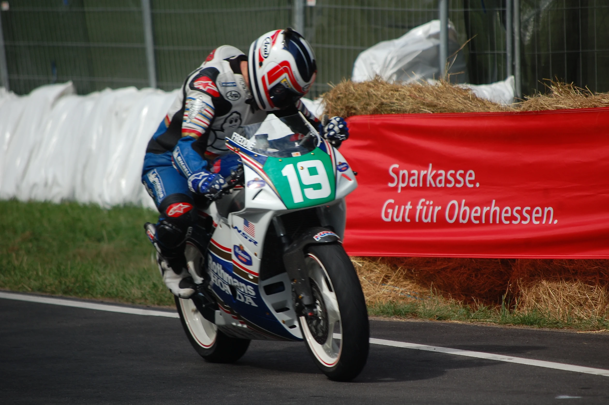 a motorcycle racer leans forward for a picture while going downhill