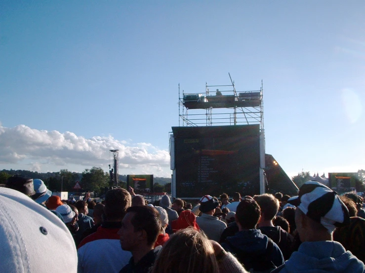 a crowd gathers at an outdoor concert in the sun