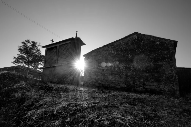 sun rays shine through the clouds on an old barn