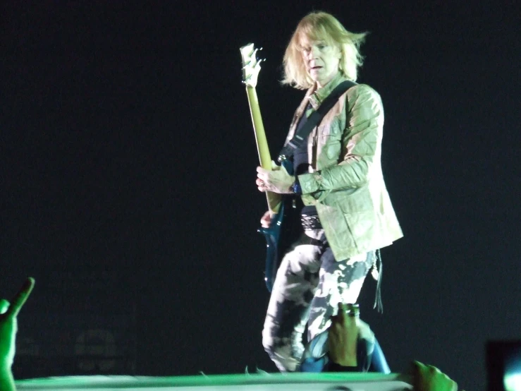 a woman playing an electric guitar while wearing green lights