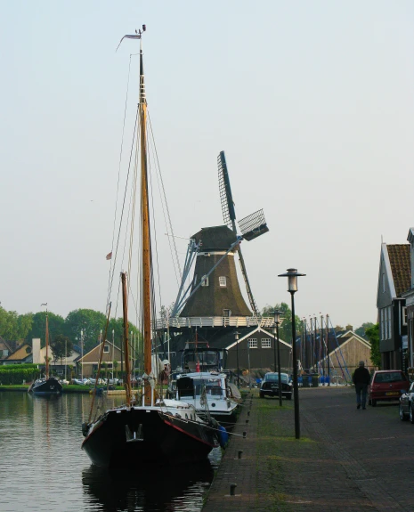a small boat sitting in the water with many buildings and windmills in the background