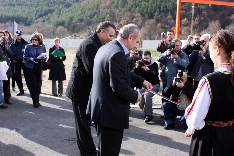 two men are shaking hands as other people watch them