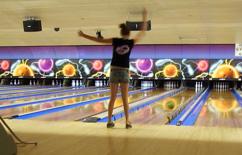 a lady throwing some bowling balls in a bowling alley