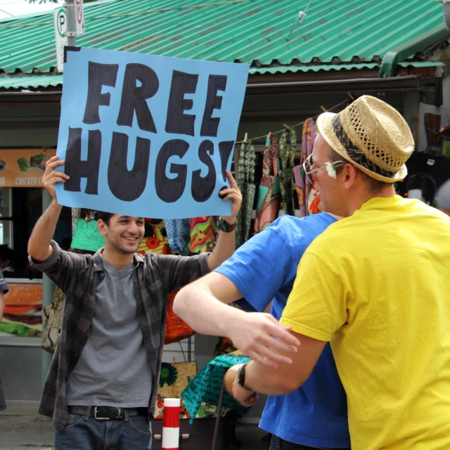 a man holding up a sign that says free hugs