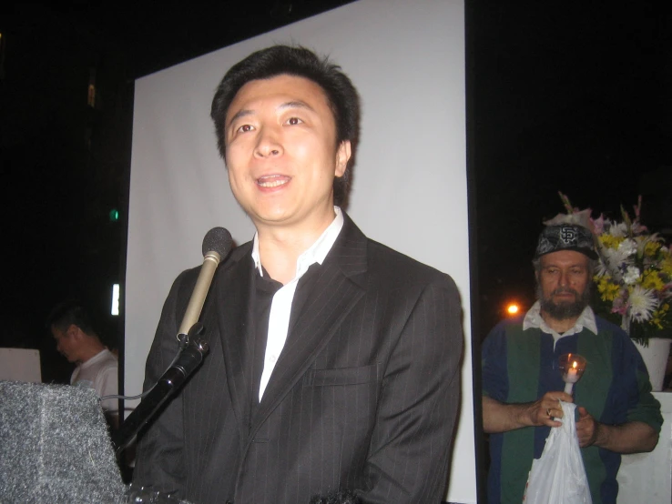 a man standing next to a microphone in front of a screen
