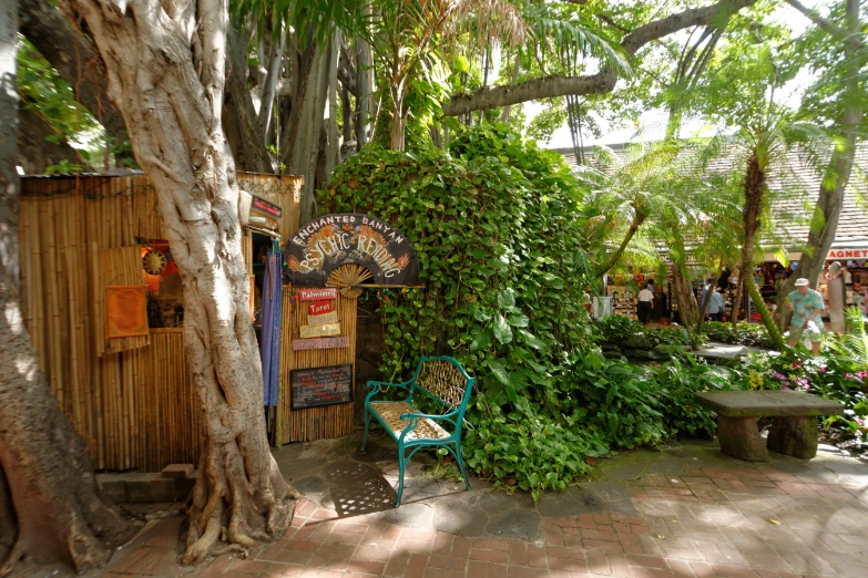 the outside of a tropical garden store with an old fence and green bench